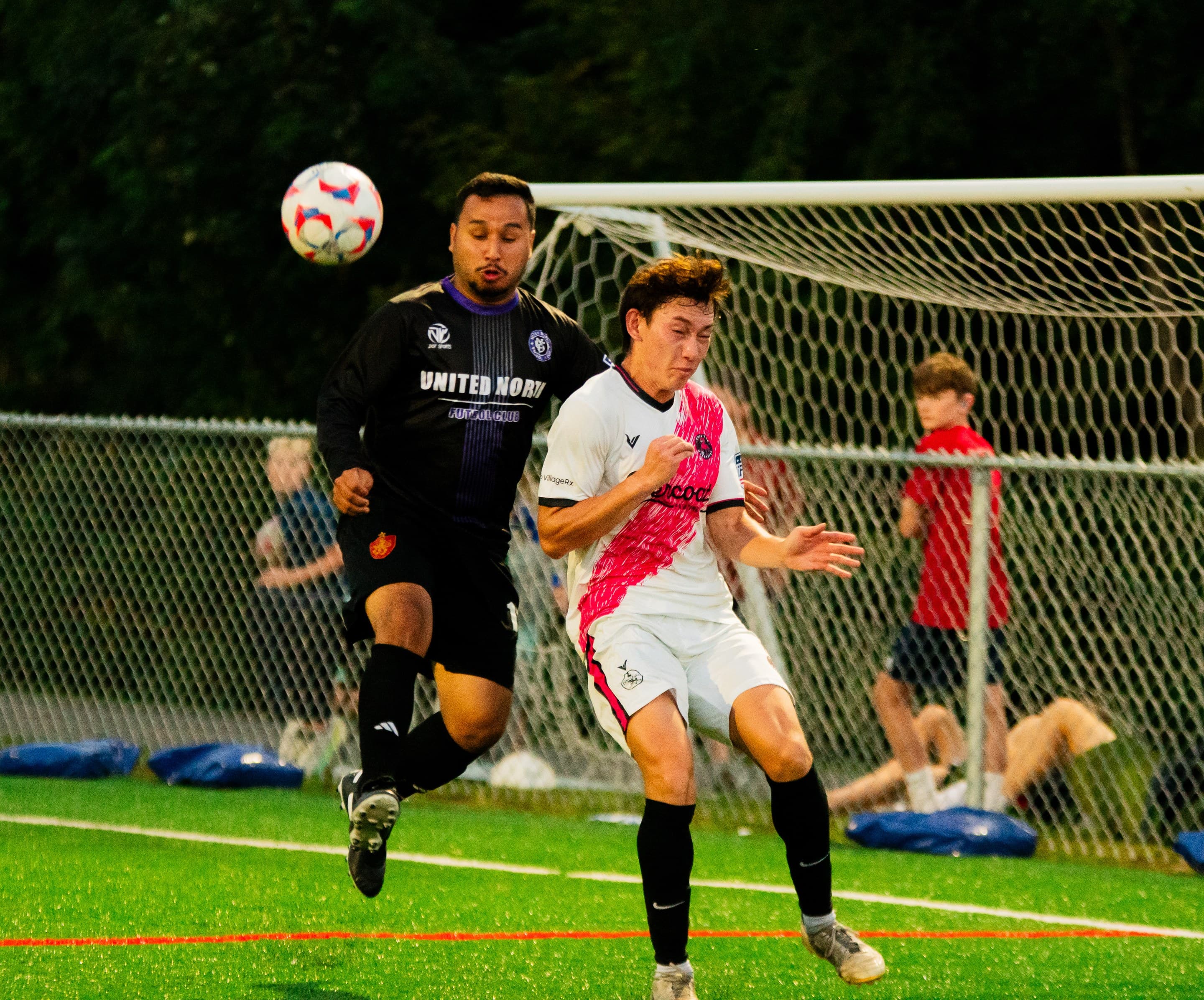 Two players challenge for a header in front of goal